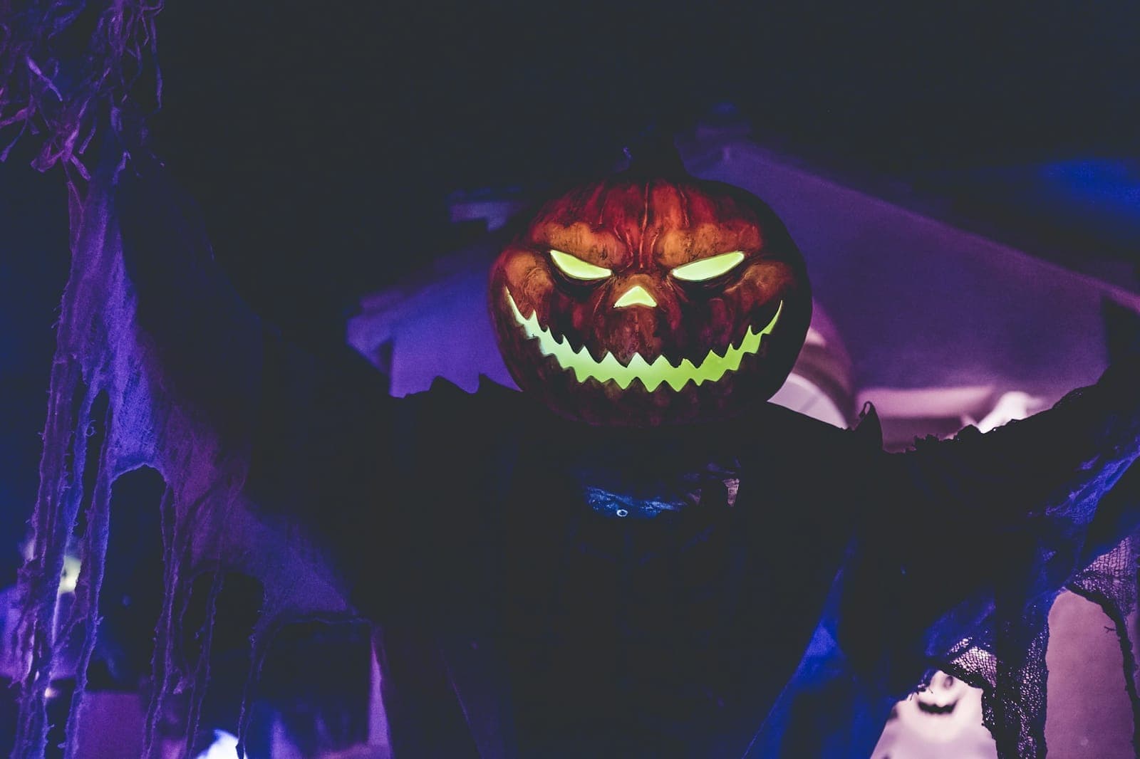 Glowing jack-o'-lantern figure under purple Halloween lights